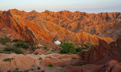 Yurt between red rocks, canyon of eroded sandstone formations, red and orange sandstone rocks,