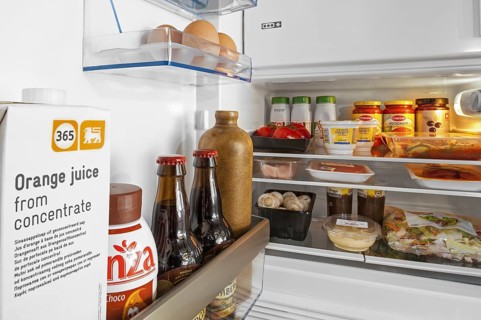 Cooled food and beverages in open fridge, refrigerator in kitchen