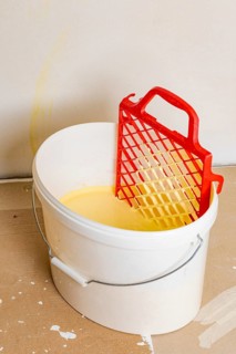 Scraper grid in bucket with yellow wall paint, painting work
