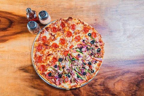 Top view of a supreme mixed pizza on wooden table. High angle view of mixed supreme pizza on wooden