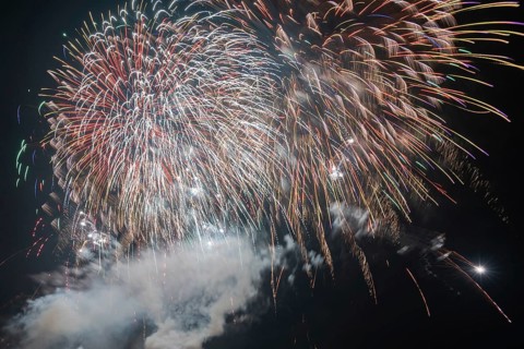 Colourful fireworks light up the night sky with sparkling lights and trails of smoke, symbolic