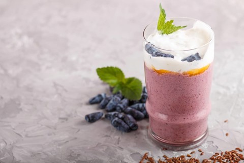 Smoothie with honeysuckle, linen and chia in a glass on gray concrete background. side view, close
