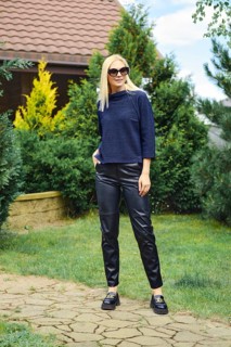 Cheerful woman in knitted blouse and leather trousers in the pathway of the garden