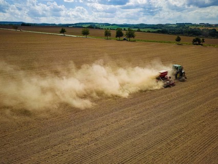 A tractor with a Horsch PRONTO DC 6 seed drill sowing in a dry field in late summer., Doma, Saxony,