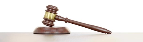 Gavel resting on a wooden table against a white background