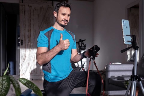 Attractive latin man personal trainer recording with phone content for online fitness business.