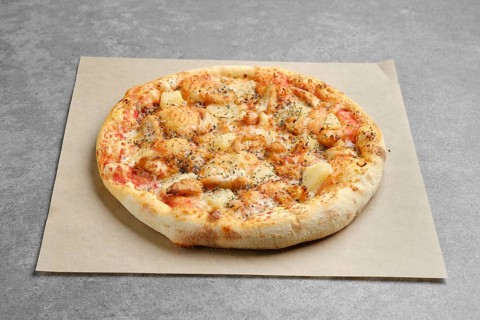 Pizza with chicken and pineapple on parchment paper