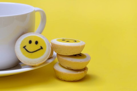 Pastry with smiley face and coffee cup, symbol