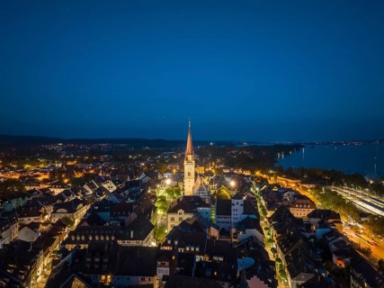 Aerial view of the city of Radolfzell at night with the illuminated Radolfzell Minster, Radolfzell