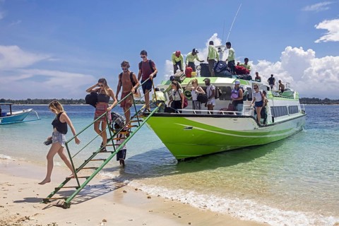 Western tourists debarking from speedboat, fast boat on the island Gili Trawangan, largest of