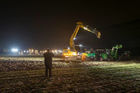 Man taking photos of excavators and tractors at a rally of farmers and peasants against the German