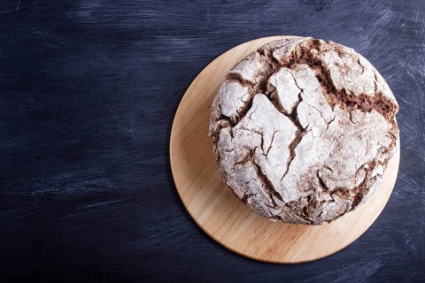Yeast free homemade bread with whole rye and wheat grains on black wooden background. Top view,