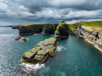 Aerial view of the ruined Castle of Old Wick surrounded by rugged cliffs on the North Sea coast,