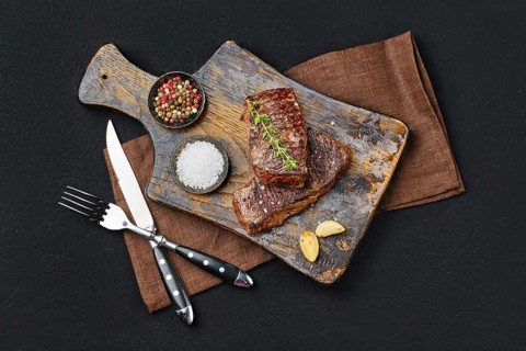 Top view of pan seared beef steak on dark background