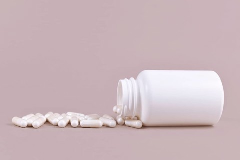 Medical capsule pills spilling from blank container
