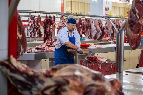 Man chopping meat and bones, butcher's shop with fresh meat, market at Osh bazaar, Bishkek,