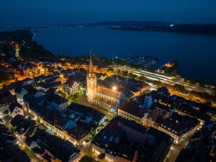 Aerial view of the city of Radolfzell at night with the illuminated Radolfzell Minster, Radolfzell