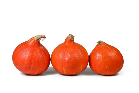 Three 'Red Kuri' squashes, also called 'Hokkaido' squash on white background