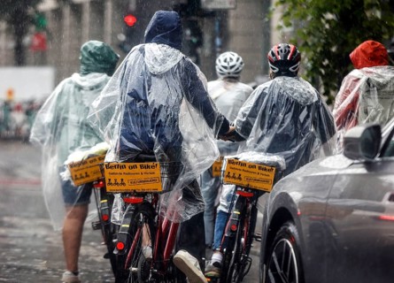 Tourists on a Berlin On Bike bike tour with rain capes in heavy rainfall, Berlin, 23 06 2023