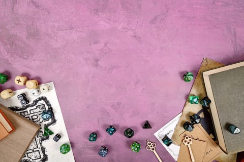 Tabletop role playing flat lay with colorful RPG dices, rule books, dungeon map on purple
