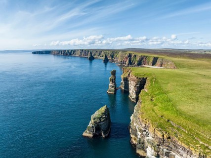 Aerial view of the rugged coastal landscape at Duncansby Head with rock tower, behind it the