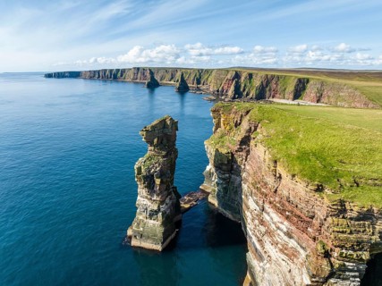 Aerial view of the rugged coastal landscape at Duncansby Head with rock tower, behind it the