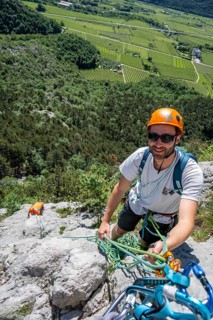 A mountaineer with helmet and safety equipment climbing on a rock face, alpine climbing with rope,