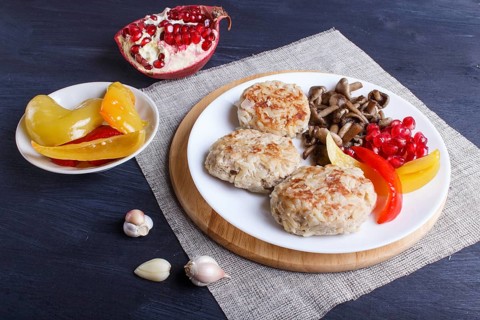 Meatballs with rice mushrooms, sweet peppers and pomegranate seeds on black wooden background.