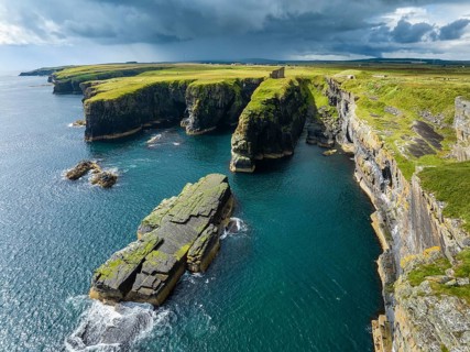 Aerial view of the ruined Castle of Old Wick surrounded by rugged cliffs on the North Sea coast,