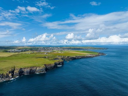 Aerial view of rugged cliffs on the North Sea coast, with the harbour town of Wick on the horizon,