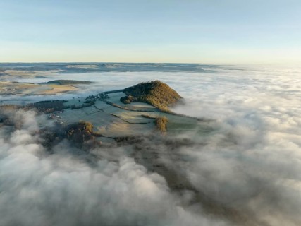 Aerial view of the wintry and fog-covered Hegaulandschaft shortly after sunrise, the volcanic cone