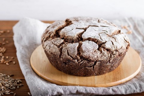 Yeast free homemade bread with whole rye and wheat grains on rustic wooden background. close up