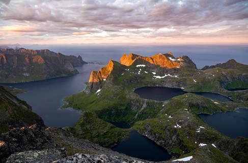View over mountain peaks and sea, dramatic sunset, from Hermannsdalstinden, with lakes