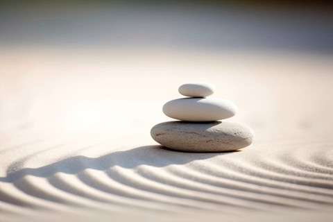 Zen stones stack on raked sand in a minimalist setting for balance and harmony. Balance, harmony,