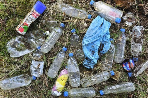 Discarded plastic bottles and other non-degradable rubbish in field