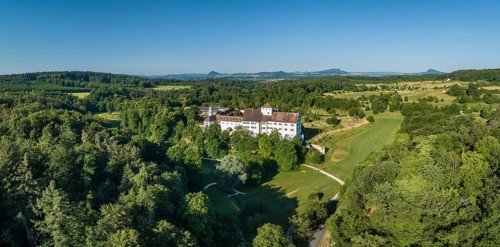 Aerial panorama of Langenstein Castle near Eigeltingen with surrounding golf course, on the horizon