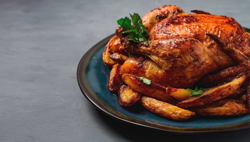 Fried whole chicken, with potatoes, on a gray background, no people