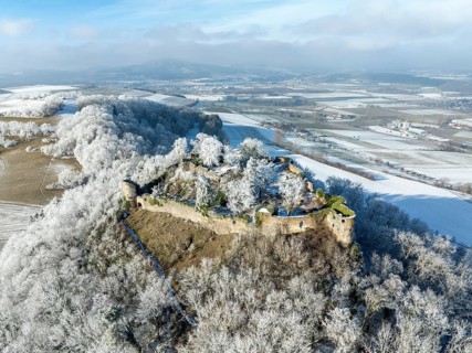 Aerial view of the snow-covered Hegau volcano MÃ¤gdeberg, with remains of a castle wall, surrounded