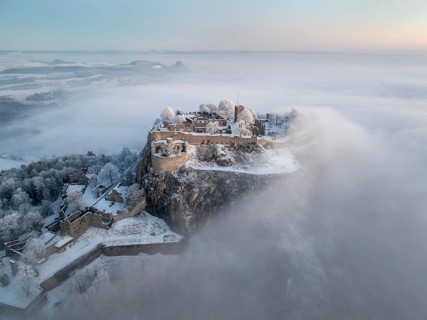 Aerial view of the Hegau volcano Hohentwiel with Germany's largest fortress ruins on a cold, foggy