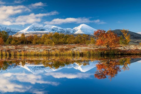 Reflection of the autumn landscape in Rondane National Park, snow-capped mountains, Doraldalen,