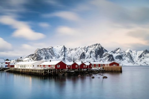 Rorbuer cabins of Hamnoy by the fjord, snowy mountains in the back, Hamnoy, Reine, Moskenesoya,