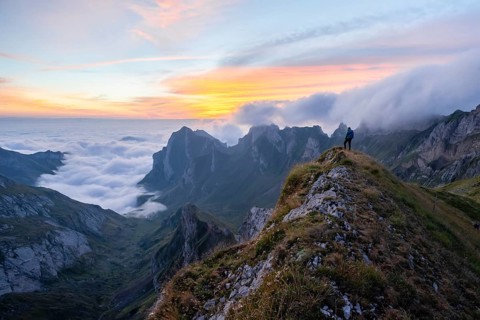 Hiker on the mountain, view over SÃ¤ntis mountains into the valley of Meglisalp at sunrise, high