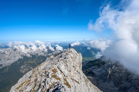 Mountaineer on a rocky narrow mountain path with mountain panorama, mountain tour to the summit of