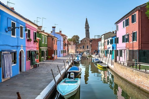 Colourful houses on the canal, canal with boats and colourful house facades, behind the church