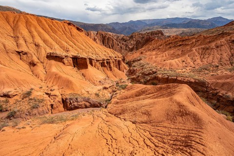 Eroded mountain landscape with sandstone cliffs, canyon with red and orange rock formations,