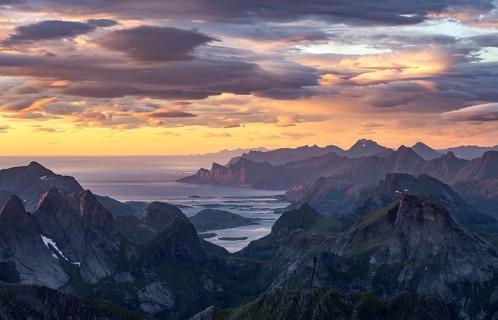 View over mountain top and sea to Fredvang, dramatic sunset, from the top of Hermannsdalstinden,