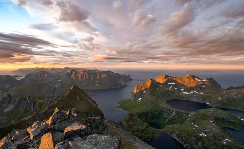 View over mountain peaks and sea, dramatic sunset, mountaineers at Hermannsdalstinden, with lakes