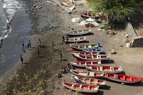 Youth playing soccer on the beach in front of traditional wooden fishing boats, Cidade Velha on the