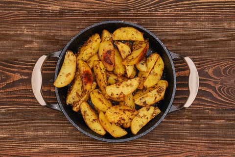 Potato wedges roasted in oven with thyme and salt, top view