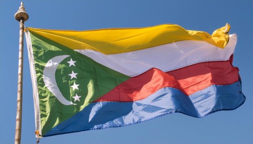 The flag of the Comoros flutters in the wind, isolated against a blue sky